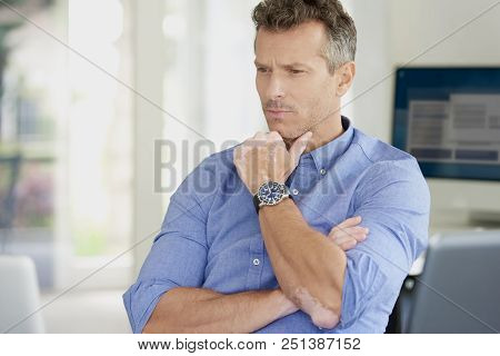 Thinking Businessman Sitting At Office Desk And Using His Laptop