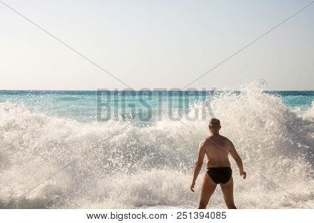 Man Chasing The Waves On Myrtos Beach, Island Kefalonia, Greece