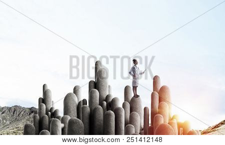 Young Female Doctor With Folder In Hands Satnding On Stone Column