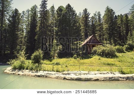 Forest And Small House In It In Summer Day. Wooden Two-storey Cottage. Cabin In The Woods. The Touri