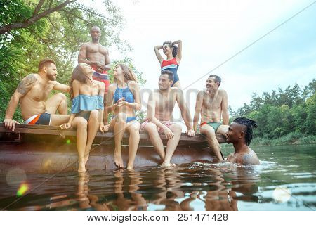 Enjoying Forest Party With Friends. Group Of Beautiful Happy Young Men And Girls Swimming At The Riv