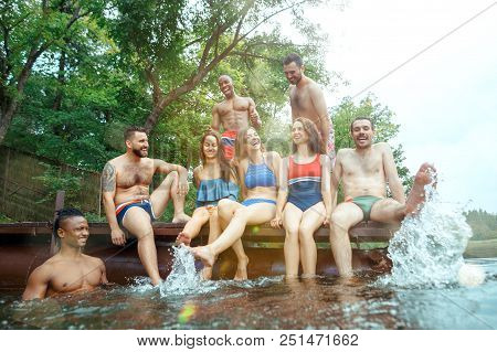 Enjoying Forest Party With Friends. Group Of Beautiful Happy Young Men And Girls Swimming At The Riv