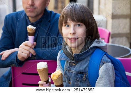 Father and son eating ice-cream in street cafe, family lifestyle. Dad with ofspring enjoying icecream spring outdoor