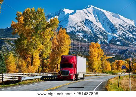 Red truck on highway in Colorado at autumn, USA. Mount Sopris landscape.