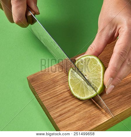 Female hands cutting organic green ripe lime with steel knife for preparation detox baverage for dietary healthy food. Concept healthy food.
