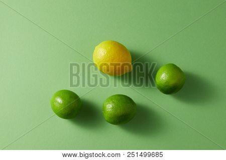 Natural ripe bright green limes and one yellow lemon on a green background. Top view.