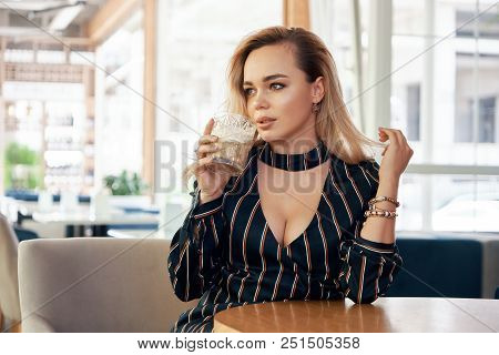 A Young, Successful Woman Having A Drink Sitting At A Table In A Modern Cafe While Waiting Her Partn