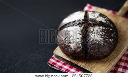 Fresh Bread On Black Chalkboard Background. Top View With Copy Space. Rye Bread On Cutting Board Clo