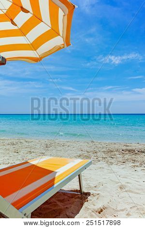 Beach Equipment, Chairs And Sun Umbrella On White Sandy Beach With Light Blue Sea Water, Beach Vacat