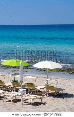 Beach Equipment, Chairs And Sun Umbrella On White Sandy Beach With Light Blue Sea Water, Beach Vacat
