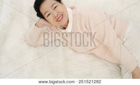 Asian Senior Woman Wear Pink Sweater Sleep On White Fur Bed