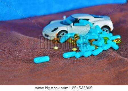 A Child's White Machine Unloads Blue Capsules And Different Tablets On A Brown Surface On A Blue Bac
