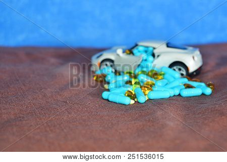 A Child's White Machine Unloads Blue Capsules And Different Tablets On A Brown Surface On A Blue Bac