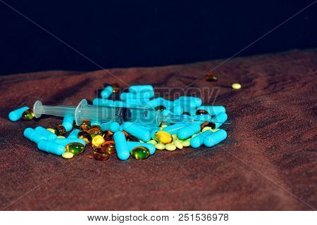 A Hand In A Blue Medical Glove Holds Medications And Pills Of Different Colors On A Black Background