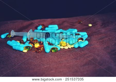 A Hand In A Blue Medical Glove Holds Medications And Pills Of Different Colors On A Black Background