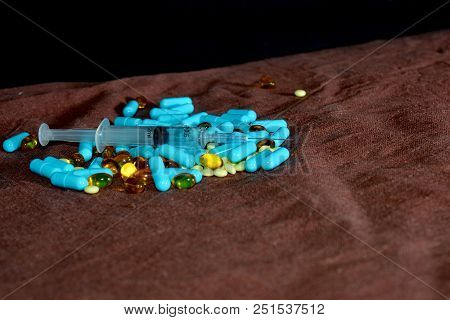 A Hand In A Blue Medical Glove Holds Medications And Pills Of Different Colors On A Black Background