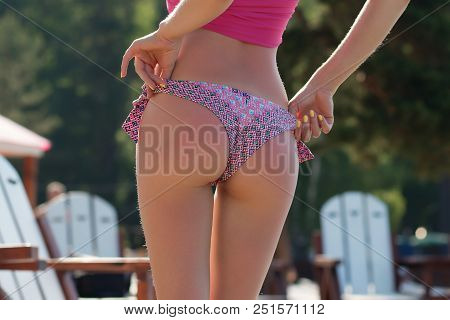 Crop Back View Of Sexy Female In Pink Ornamented Bikini Bottom Standing On Wooden Platform At Water 