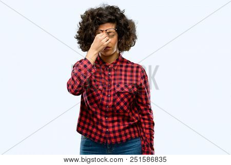 Beautiful arab woman with sleepy expression, being overworked and tired, rubbes nose because of weariness