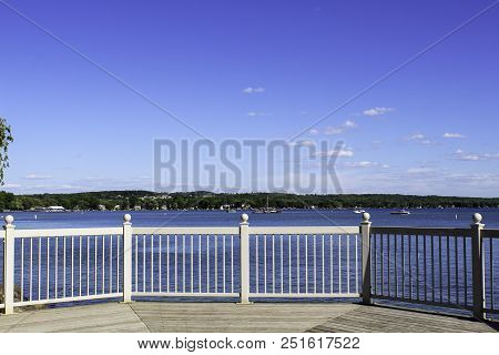 View Of Canandaigua Lake From The Gazebo In The Park. Calm Water And Blue Sky. Looking Across The La