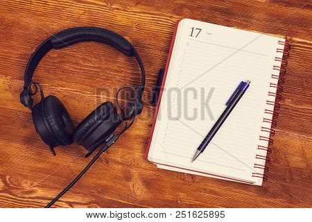 Blank Notepad With A Pen And Headphones On Vintage Wooden Table Background. Template For Design Pres
