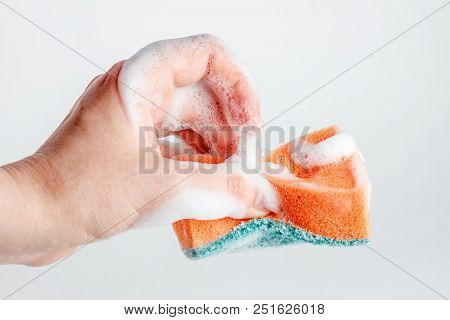 Hand Grasps Sponge For Washing Dishes On White Background