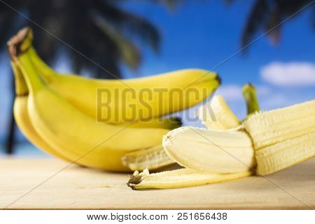 Lot Of Whole Fresh Yellow Banana One Cluster And Opened Like A Plane With Palm Trees On The Beach In