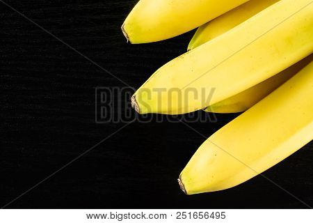 Group Of Five Whole Fresh Yellow Banana Flatlay On Black Wood