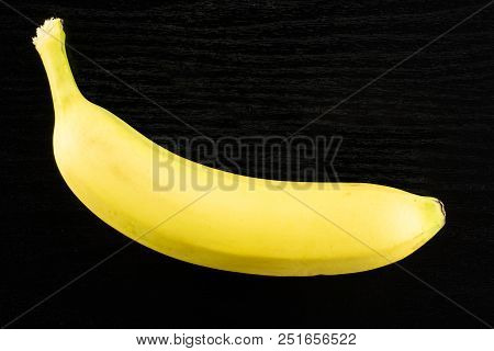 One Whole Fresh Yellow Banana Flatlay On Black Wood