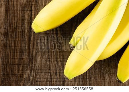 Group Of Five Whole Fresh Yellow Banana Flatlay On Brown Wood