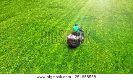 A Lawnmower With Worker. Grass Cutting Background.