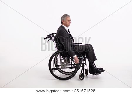 Side View Of Aged Man Sitting In Wheechair. Elderly Man Wearing Formal Office Clothes Sitting In Whe