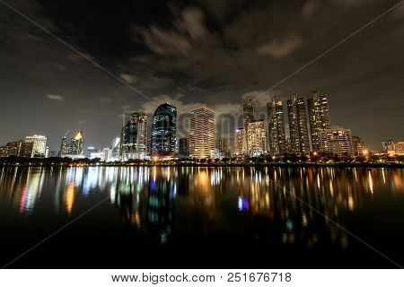 Night Sky Of Panorama View , Cloud Flow Over Modern Buildings Of Benchakitti Park With Lights Reflec