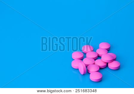 Bright Pink Pills On A Blue Background. The Location In The Bottom Corner Of The Image.