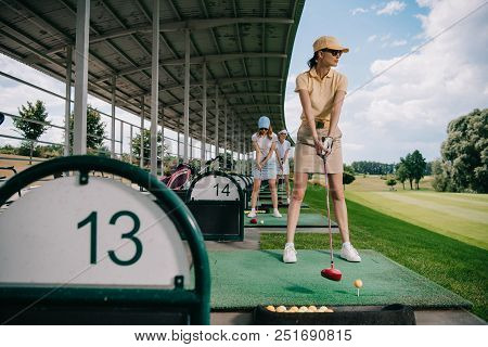 Women In Caps With Golf Clubs Playing Golf At Golf Course
