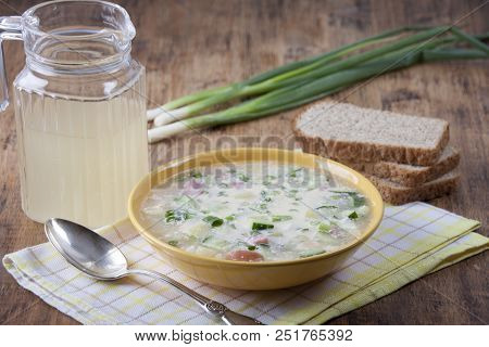 Okroshka On Kvass In A Yellow Plate And A Jug Of Kvass On A Wooden Table