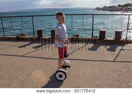 Child On Hover Board. Kids Riding Scooter In Summer Near The Sea. Balance Board For Children. Electr