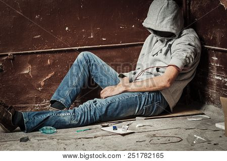 A Man Is A Drug Addict With A Syringe Using Drugs Lying On The Floor. The Concept Of Anti Drugs. Mal