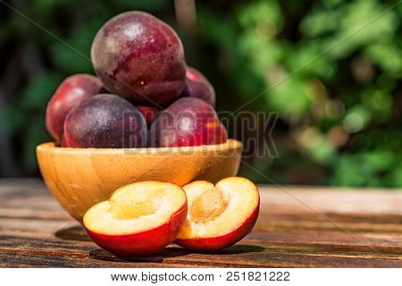Close Up Fresh Plumcot, Interspecific Plums Variety In Wooden Bowl On Wooden Table. Selective Focus,
