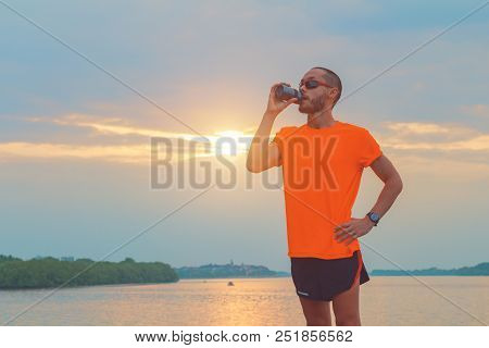 Tired Jogger Making A Pause And Drinking Water.