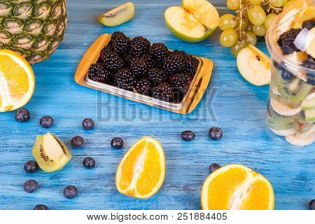 Fruit Salad In Plastic Cup Next To Berried And Other Exotic Fruits On Wooden Table. Delicious Colorf