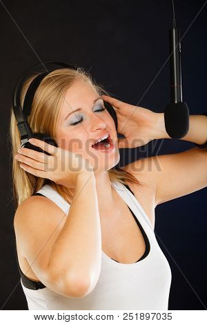 Music, Passion, Stage-fright Concept. Blonde Young Woman Singing To Microphone And Wearing Big Headp