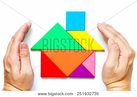 Color Wood Tangram In Home Shape With Cover Hand On White Background (concept Of Home Or Family Prot