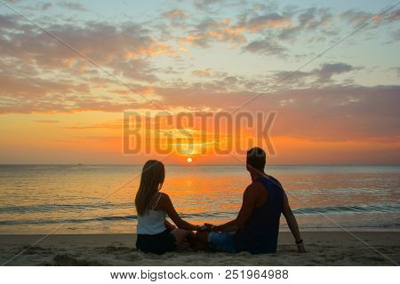 Couple Watching The Sunset On The Beach