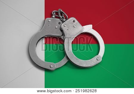 Madagascar Flag  And Police Handcuffs. The Concept Of Observance Of The Law In The Country And Prote
