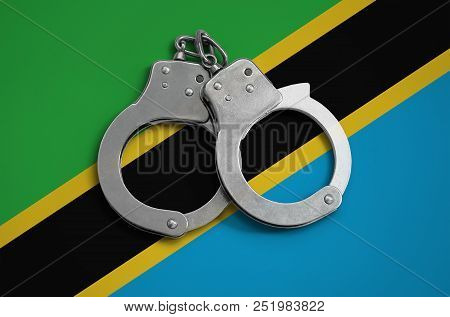 Tanzania Flag  And Police Handcuffs. The Concept Of Observance Of The Law In The Country And Protect
