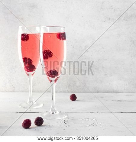 Kir Royal Champagne Cocktail On White, Copy Space. Flute Glasses With Berry Sparkling Champagne Drin