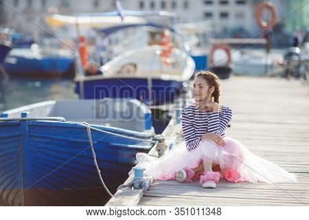 Happy Young Womanl With A Long Braid Happy Laughing While Sitting Outdoor With Boats On Background. 
