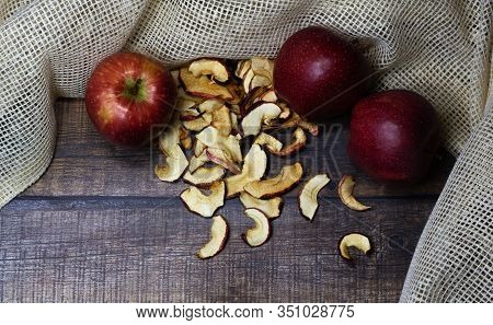 Dried Apple Chips And Three Red Apples On A Brown Wooden Table. Organic Natural Food. Close Up. Top 