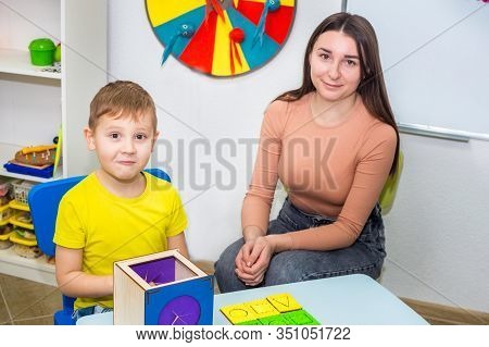 Speech Therapy. A Young Speech Therapist Is Engaged In Cubes With A Boy. Learning The