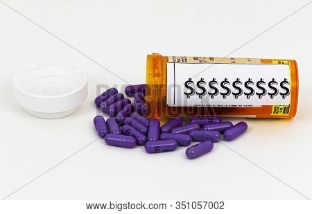 A Prescripeion Bottle Has Dollor Signs On It As It Is Laying On Its Side With Purple Pills Spilling 